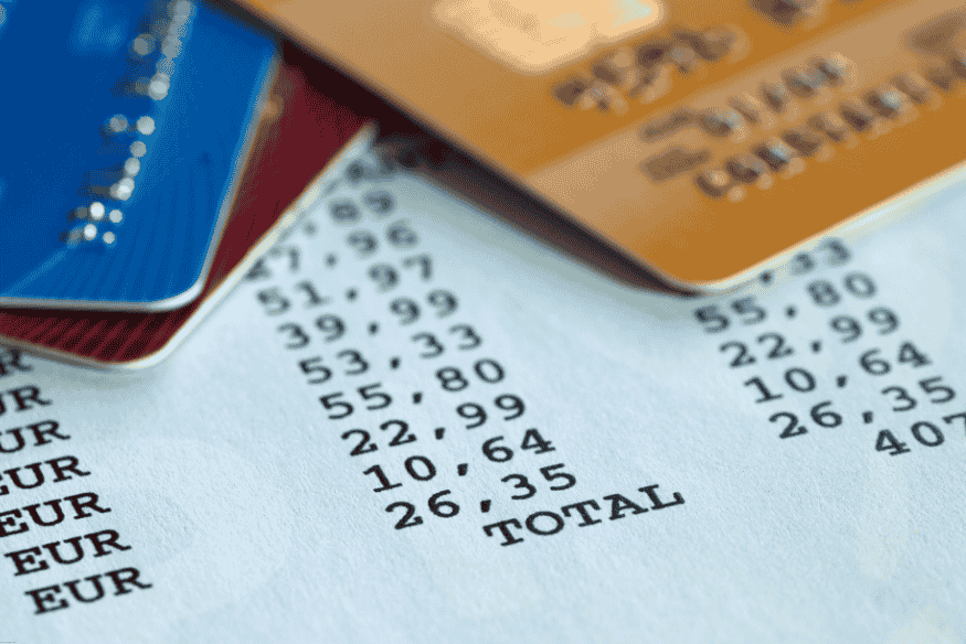 Tarjetas de crédito sobre un recibo con montos en euros y total final.