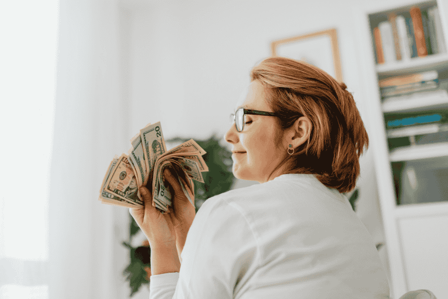 Persona sosteniendo billetes como símbolo de ahorro al comparar precio por unidad en las compras