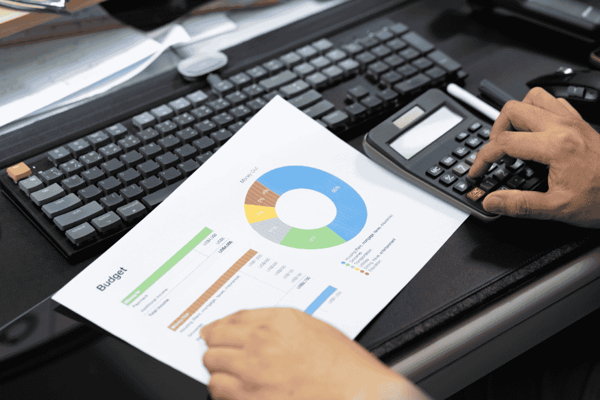 Persona usando calculadora y gráficos para organizar el presupuesto de vacaciones