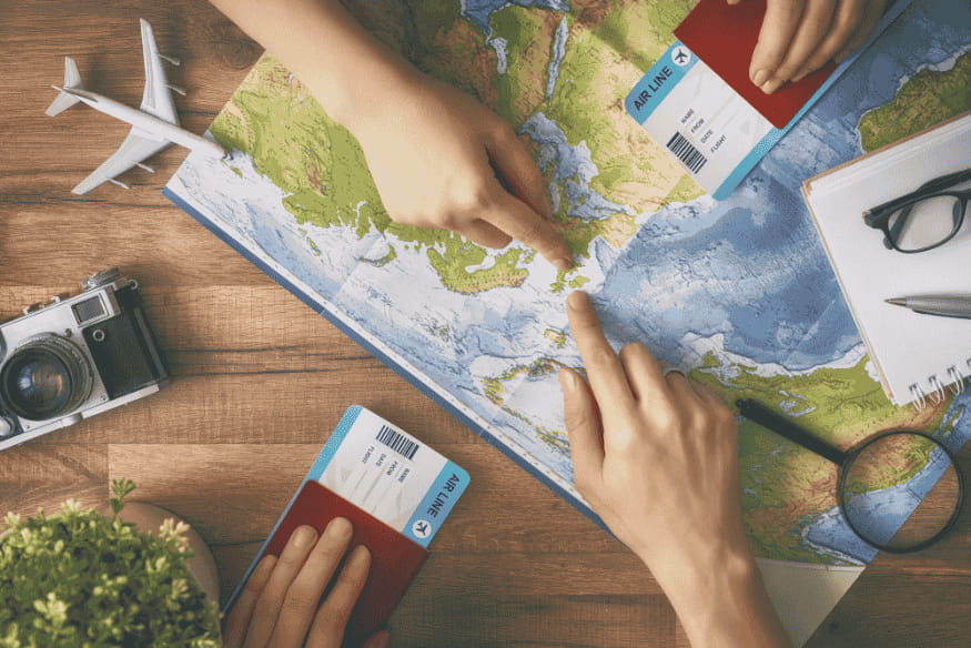 Personas planificando un viaje sobre un mapa con billetes de avión para presupuestar vacaciones