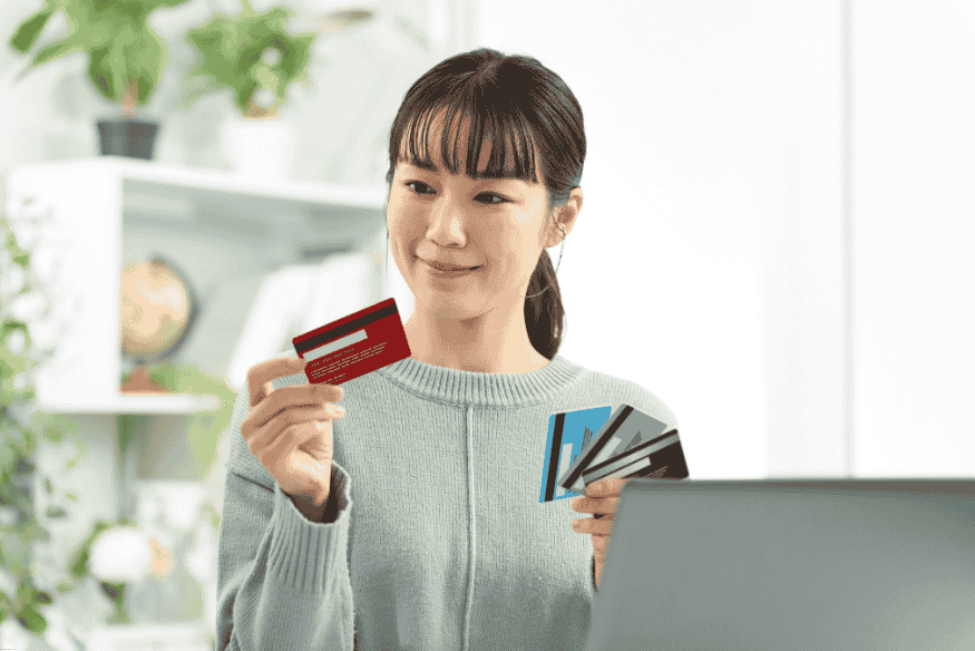 Mujer comparando varias tarjetas de crédito frente a su laptop