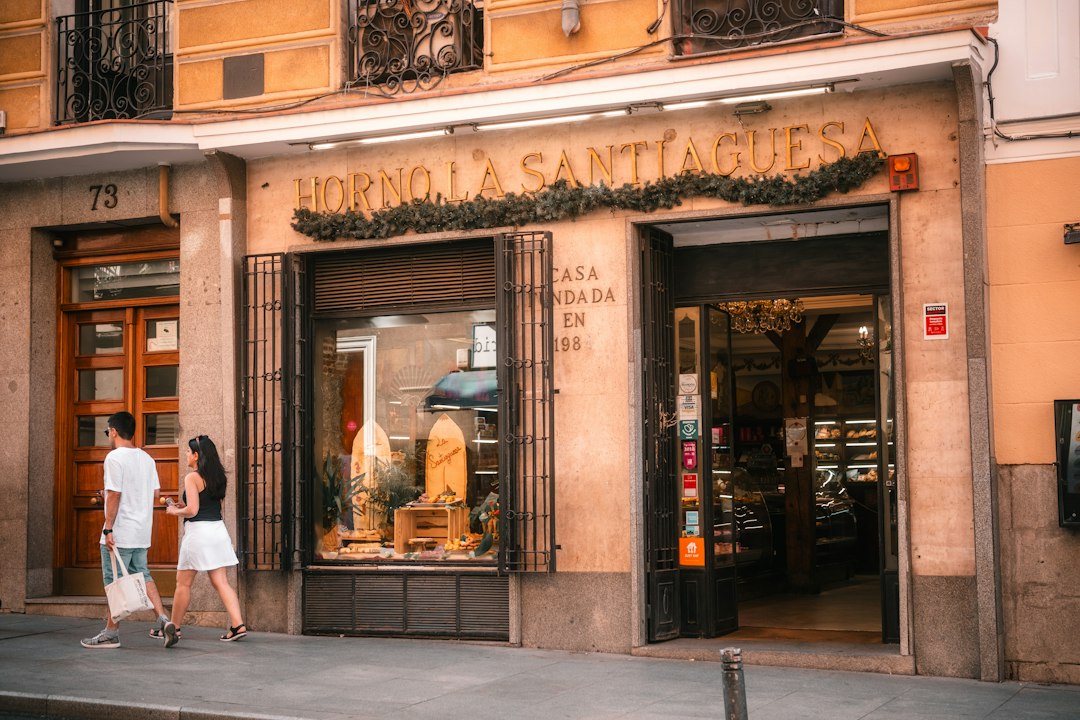 A man and a woman walking past the Horno La Santiaguesa bakery in Madrid