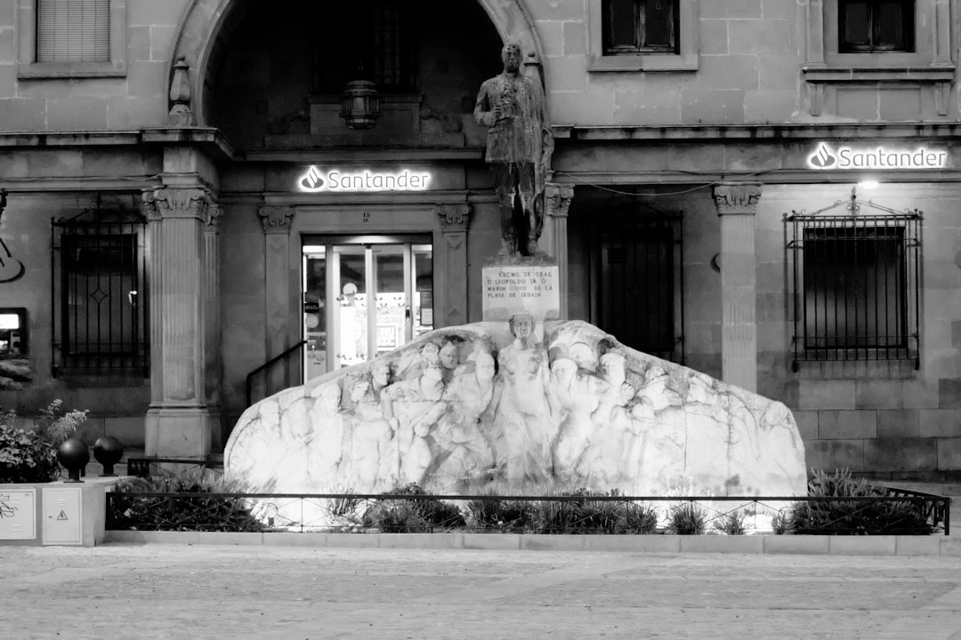 A stone statue of a man above a relief sculpture in front of a building