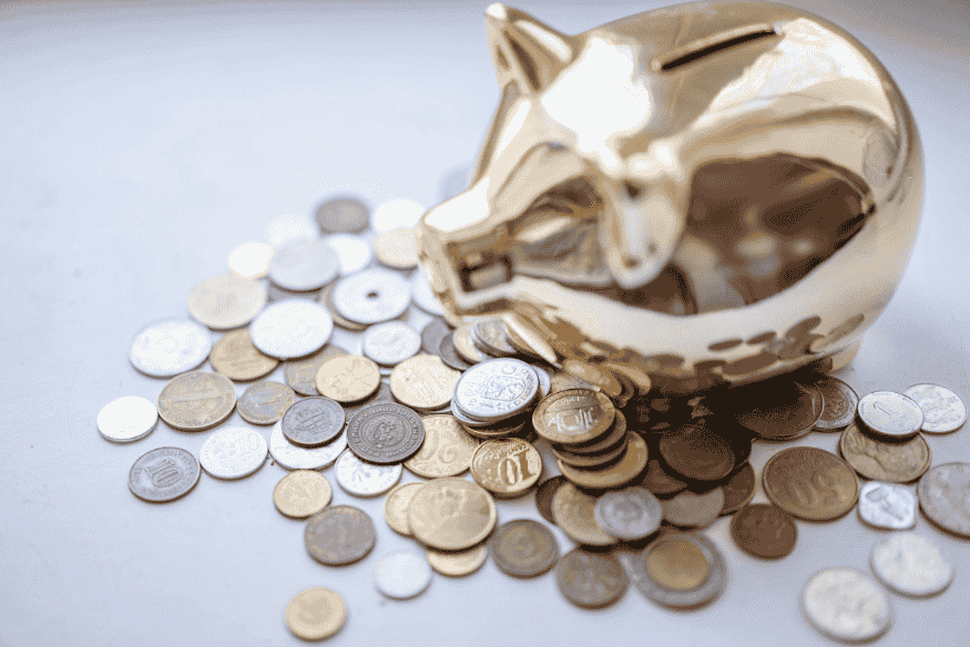 Alcancía dorada rodeada de monedas como símbolo de ahorro por objetivos financieros