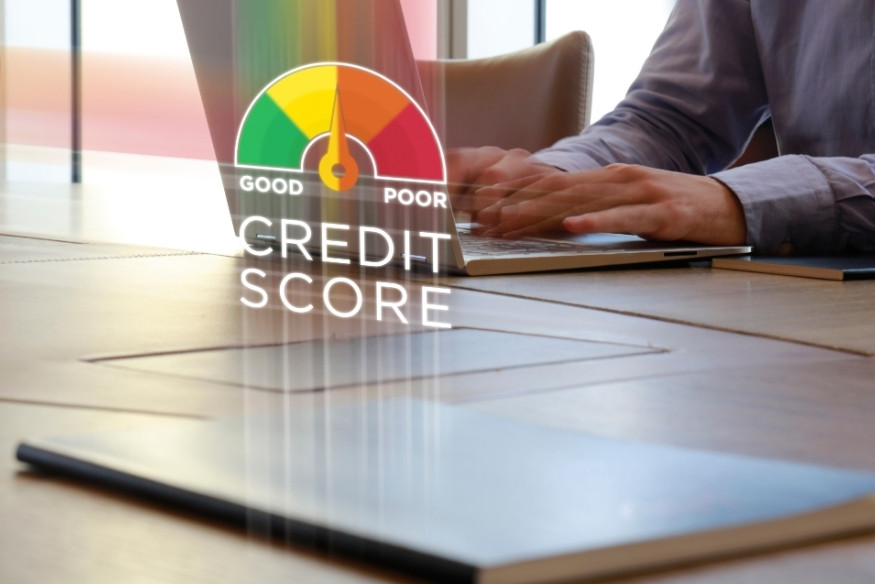 Persona trabajando en laptop con indicador digital de puntaje crediticio que muestra nivel de crédito.