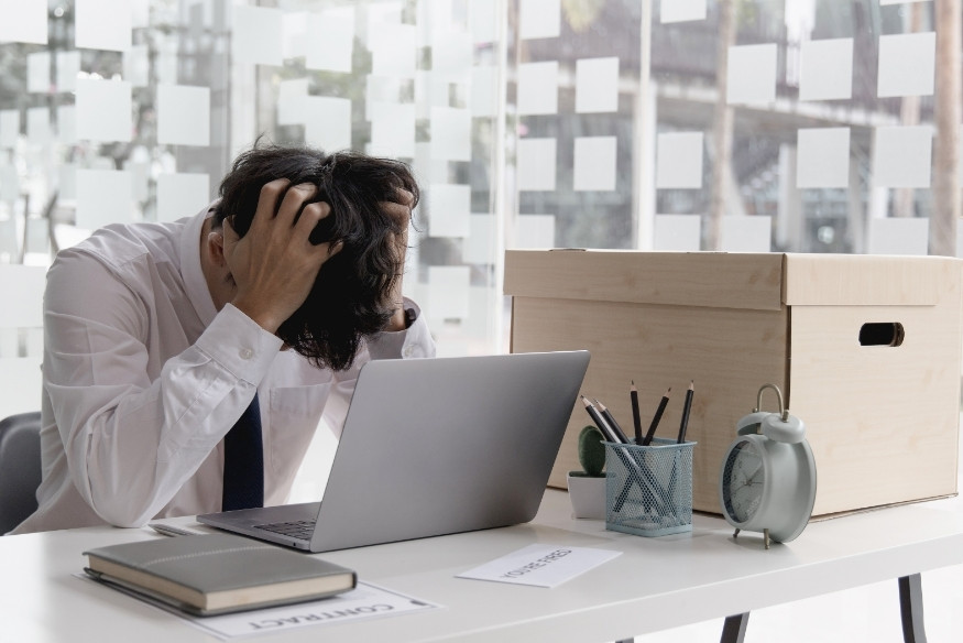 Persona en oficina con expresión de frustración frente a una computadora portátil.