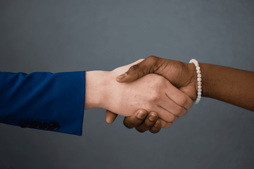 Apretón de manos entre dos personas de diferentes tonos de piel, simbolizando un acuerdo.