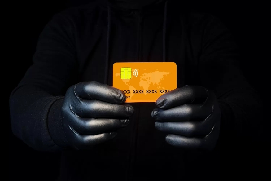 Persona con guantes sosteniendo una tarjeta de crédito robada