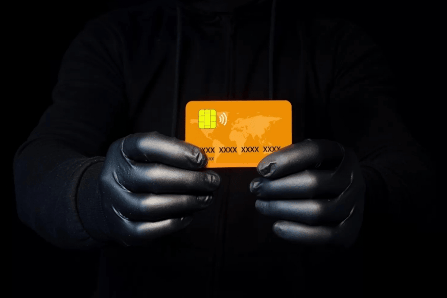 Persona con guantes sosteniendo una tarjeta de crédito robada