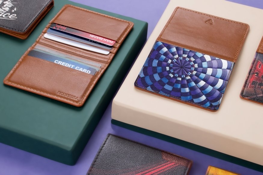 Varias carteras y tarjeteros de cuero con tarjetas guardadas, sobre cajas de presentación.