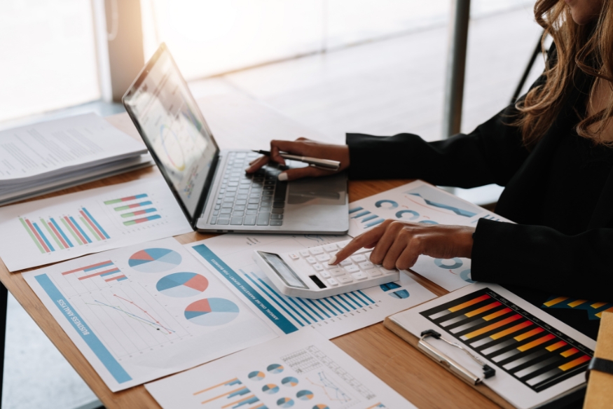 Análisis financiero con calculadora, laptop y gráficos para planificar compras grandes con tarjeta de crédito