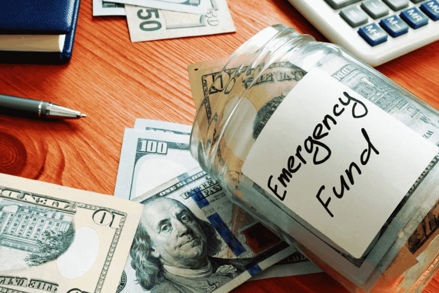 Tarro de vidrio con billetes de dólar etiquetado como "Emergency Fund".