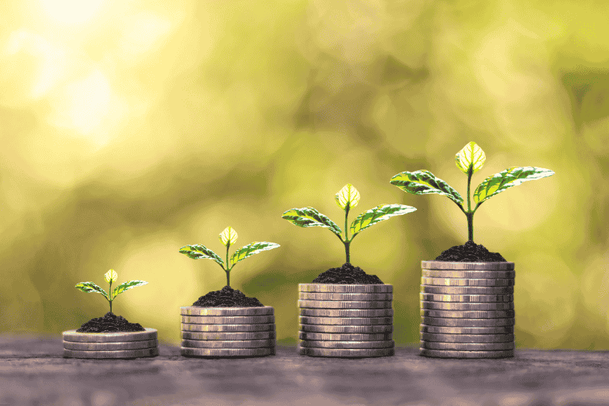 Pilas de monedas creciendo con plantas brotando en la cima, representando crecimiento financiero.