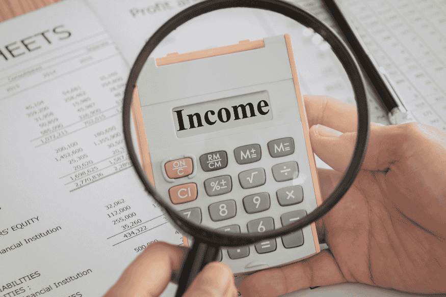 Calculadora con la palabra "Income" en la pantalla y documentos financieros de fondo.