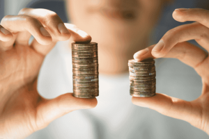 Persona comparando dos pilas de monedas de diferentes alturas.