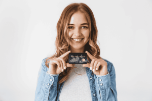 Mujer joven sonriendo mientras sostiene una tarjeta de crédito
