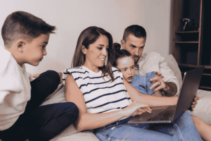 Familia reunida en el sofá usando una laptop y una tarjeta de crédito.