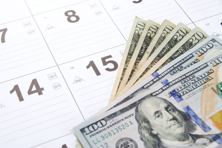 Billetes de dólar sobre un calendario, simbolizando pagos en fechas específicas.