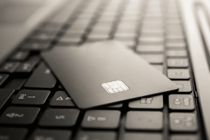 Tarjeta de crédito negra sobre un teclado de computadora portátil, simbolizando la gestión financiera digital.