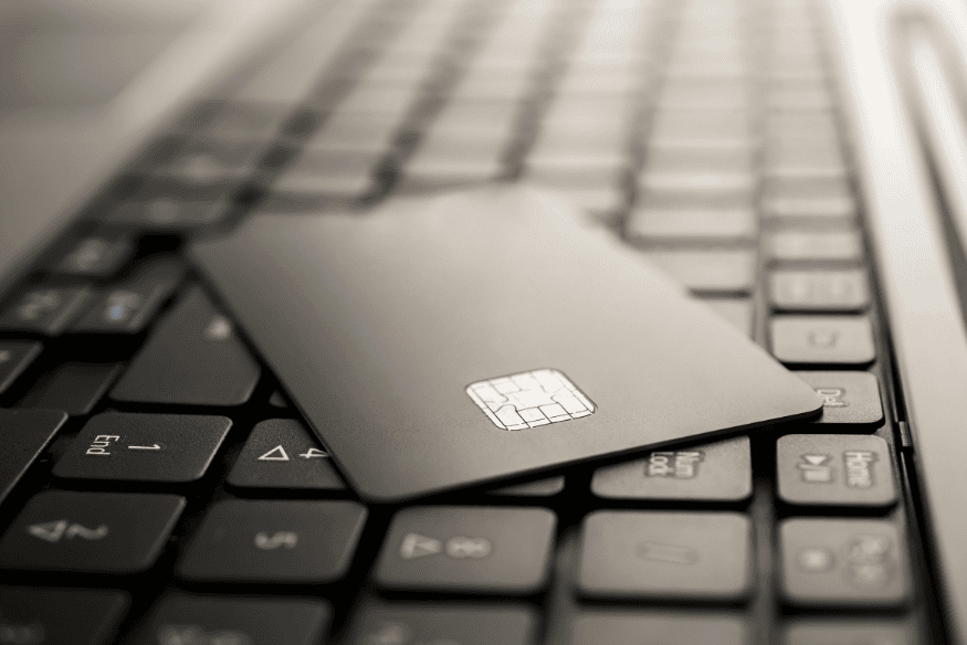 Tarjeta de crédito negra sobre un teclado de computadora portátil, simbolizando la gestión financiera digital.