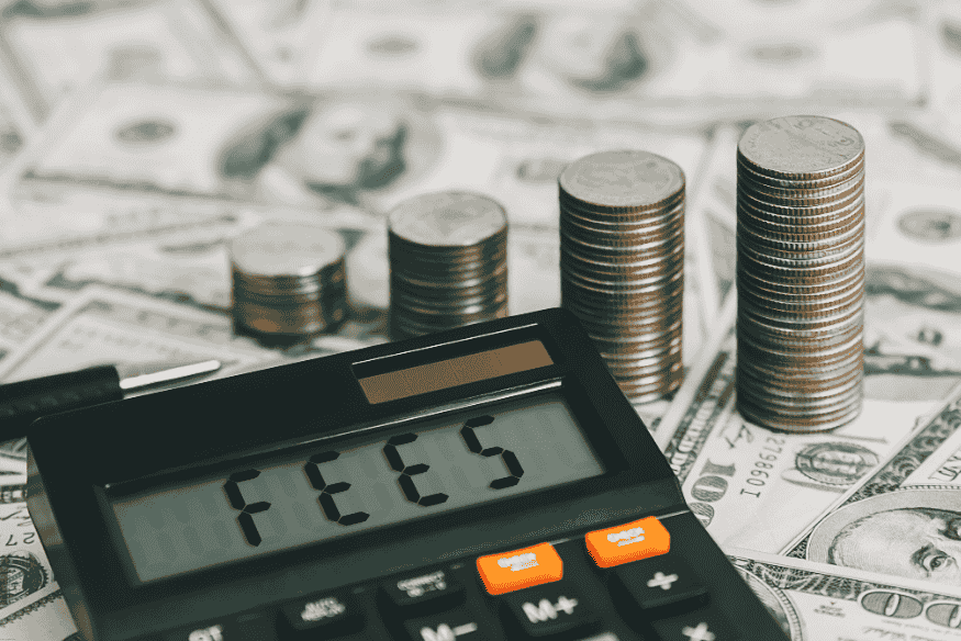 Calculadora con la palabra fees junto a monedas apiladas