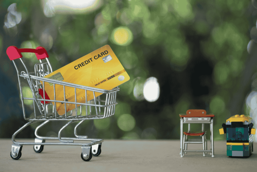 Tarjeta de crédito dorada en carrito de compras de juguete