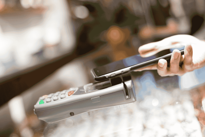 Persona realizando pago sin contacto con smartphone en terminal de punto de venta.
