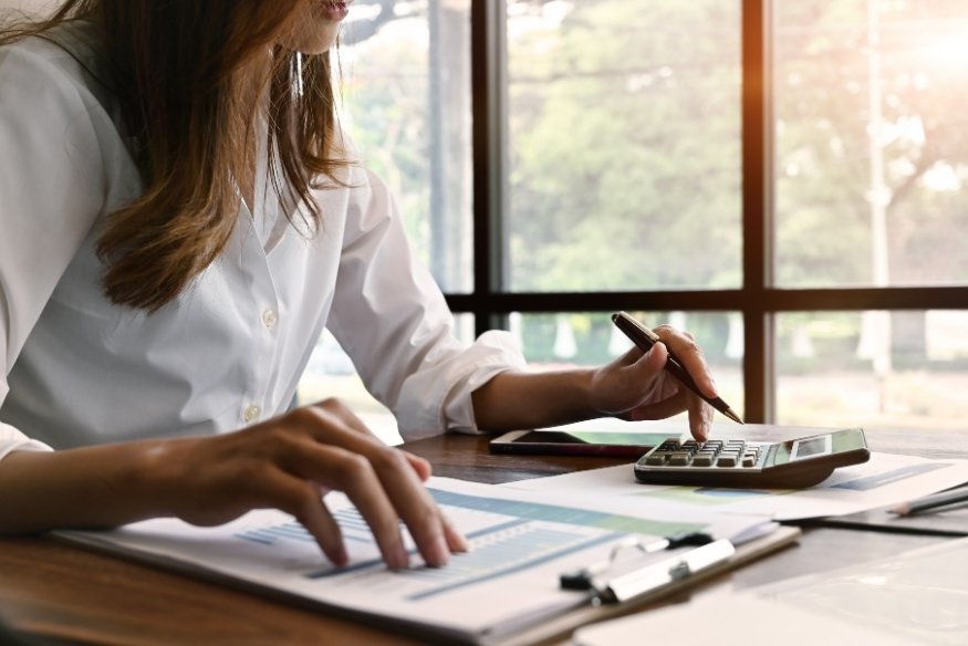 Persona usando una calculadora para revisar documentos financieros.
