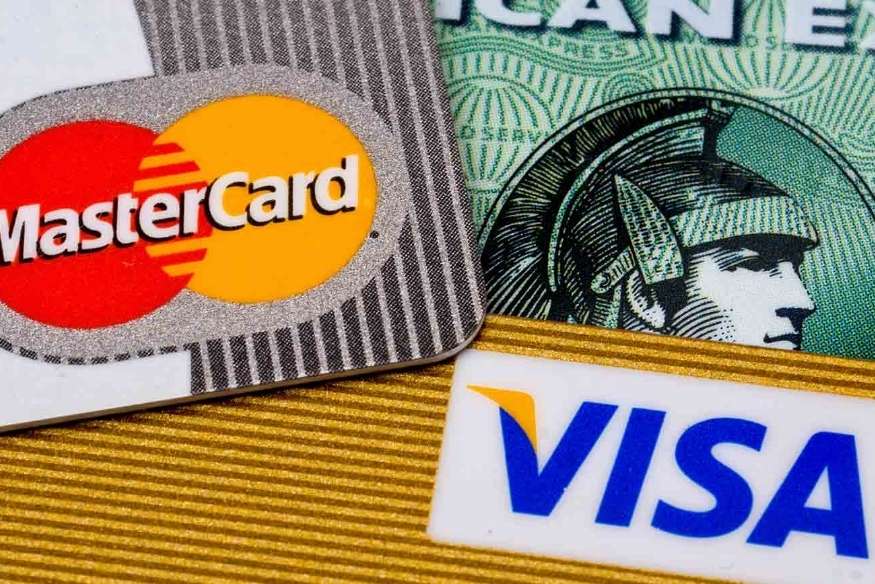 Cartões das bandeiras MasterCard, American Express e Visa sobre fundo dourado.
