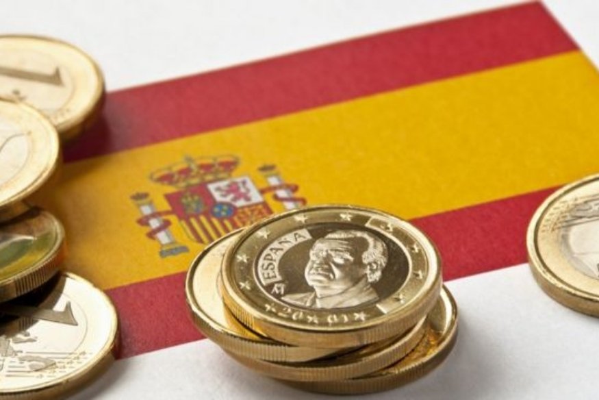 Moedas de euro sobre a bandeira da Espanha.