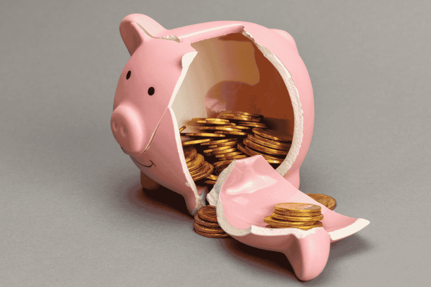 Alcancía rota con monedas representando desorganización financiera antes de usar sobres digitales